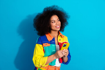 Bright portrait of a young woman in a colorful patchwork jacket smiling and looking off to the side...