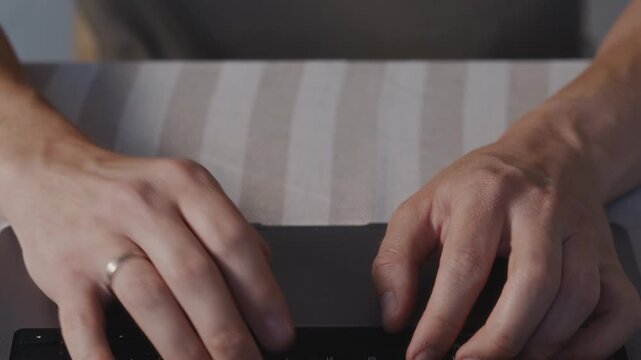 Close up of male hands pressing keys on a laptop keyboard. Measured working rhythm, soft light and concentrated everyday computer activity indoors. High quality 4k footage