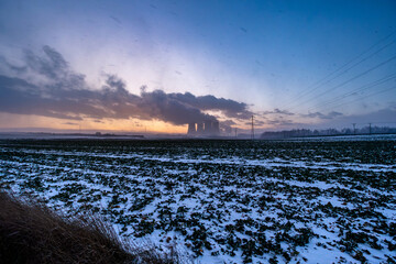 Cooling towers of the nuclear power plant. Large smoking cooling towers in the evening in winter at sunset.
