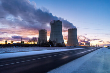 Cooling towers of the nuclear power plant. Large smoking cooling towers in the evening in winter at sunset.