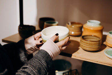 Woman touching handcrafted ceramics in cozy craft decor shop.
