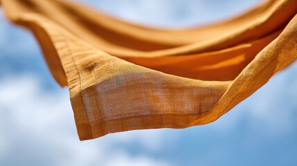 Orange fabric flowing in wind against blue sky