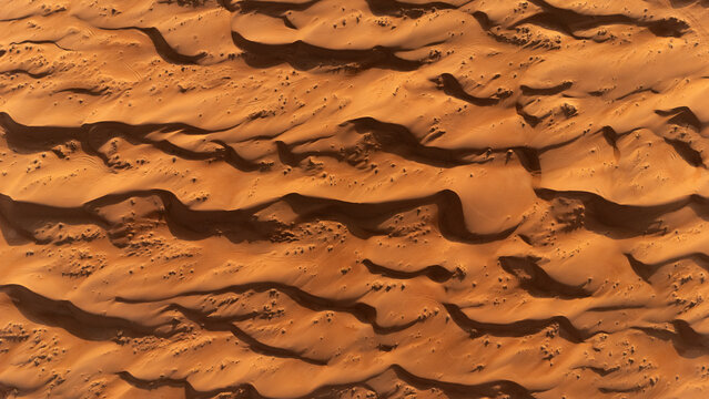Aerial view of the shifting sands creating mesmerizing patterns of light and shadow across the vast desert landscape, Bidiyah, Ash Sharqiyah North Governorate, Oman.