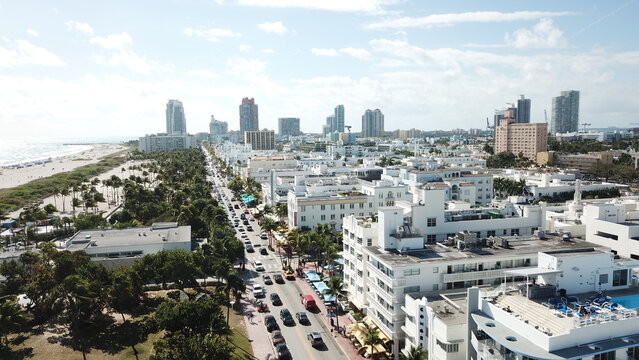 Aerial view of Ocean Drive lined with art deco buildings and a bustling street, contrasted against the vast Atlantic, West Palm Beach, Florida, United States.