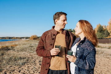 Happy beautiful couple in love enjoying autumn picnic on coast in open air. Weekend and lifestyle concept. High quality photo