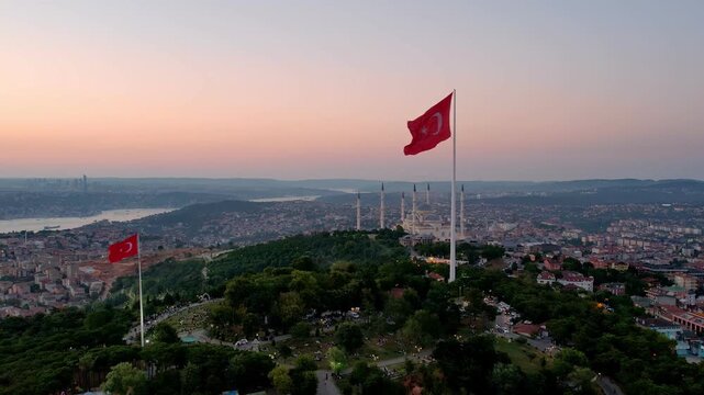 Drone footage showing Camlica Mosque, the large Turkish flag, the Bosphorus and Istanbul skyline illuminated by the warm light of the sunset.