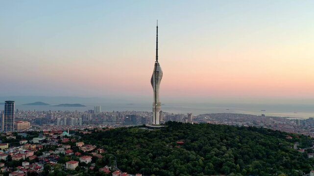 Drone footage showing Camlica Tower rising above Istanbul&rsquo;s skyline, surrounded by forests, residential areas and the Marmara Sea under warm sunset light.