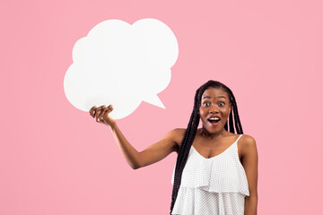 Shocked Afro woman holding blank speech bubble with mockup for ad design on pink studio background....
