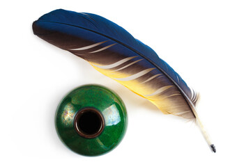 Feather and green ink well on a white background. The tools are prepared for writing or calligraphy