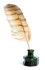A feather quill is placed in an old green ink bottle.  Old writing tool and ink bottle on a white