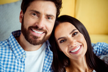 Happy couple indoors in a cozy living room, smiling at the camera, enjoying time together at home,...