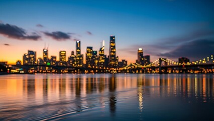 Obraz premium Bokeh city skyline at sunset or sunrise reflecting on still water. Urban landscape with blurred lights for background or cityscape.