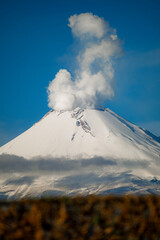 Breathtaking view of Popocatepetl volcano in Mexico, featuring a snow-capped summit emitting a large smoke plume under a clear blue sky