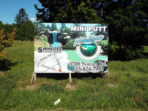Orleans, ON, Canada-July 3,2025:A billboard for "Mer Bleue Mini Putt" features a waterfall, course map, and contact details, located five minutes away at 3708 Navan Road.