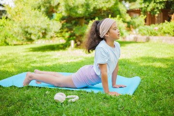 Girl practicing yoga on a mat in the garden