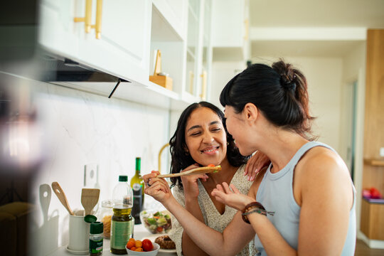 Young adult couple cooking together in modern home kitchen, playful