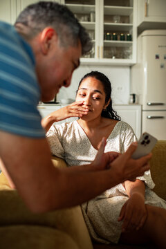 Mature man and young adult woman worried over phone in home kitchen