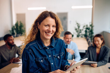 Fototapeta premium Happy businesswoman using touchpad during meeting in office and looking at camera.
