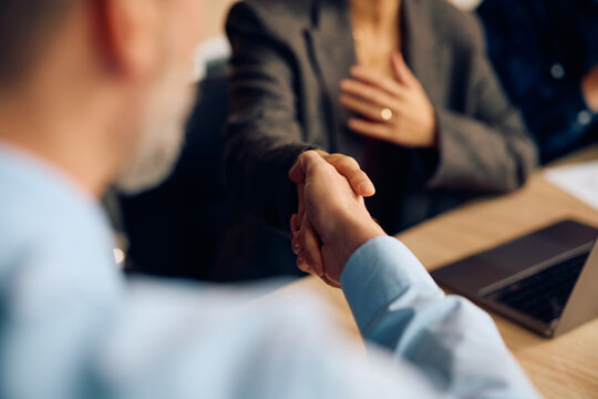 Close up of business people shaking hands on meeting in office.