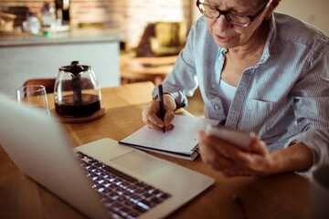 Senior woman focused on budgeting at kitchen table