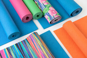 Colorful yoga mats and sheets arranged on a white surface for practice and relaxation at a studio