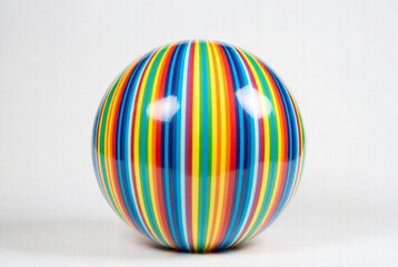Colorful striped ball rests on a light surface in an indoor setting with no visible people around