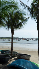 Traditional Vietnamese basket boats on a sandy tropical beach with palm trees. Coastal fishing culture, travel and tourism concept in Vietnam, sunny day and calm atmosphere.