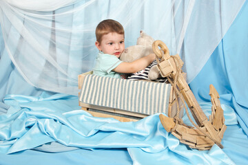 Young boy sitting in a boat with a stuffed animal at the dock, pondering the mysteries of the sea.