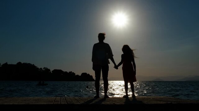 Silhouette on mum and child on bay. A mother with her child silhouette pass free time on the pier during summer golden hours