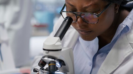 Microscope close up of woman arranging sample tray for experiment in chemistry lab. Detailed investigation of specimen for medical research and nanotechnology, biotechnology solutions.