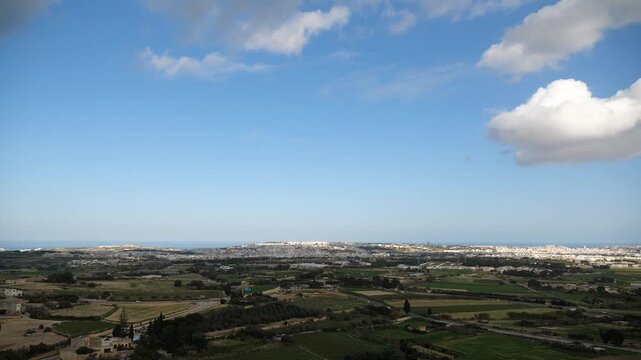 Panoramic rural landscape view of fields, houses, and distant city with sea and sky on a partly cloudy day in Malta.
malta, landscape, view, pano