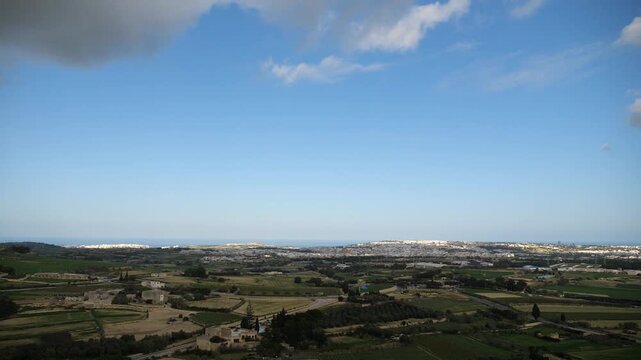 Panoramic rural landscape view of fields, houses, and distant city with sea and sky on a partly cloudy day in Malta.
malta, landscape, view, pano