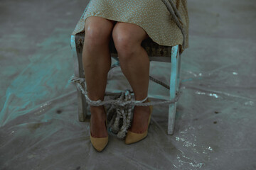 Top view of young woman are tied up with a rope to a chair in the basement. Kidnapping, violence...
