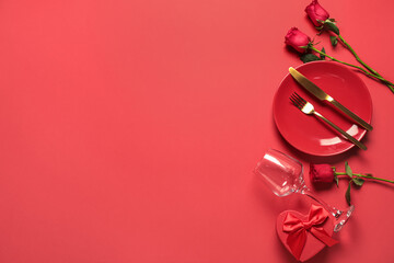 Beautiful table setting for Valentine's Day with rose flowers and gift box on red background