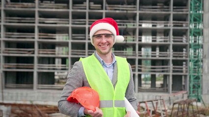 Cheerful foreman posing for camera against unfinished multi-story house