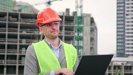 Displeased construction manager entering data into laptop during on-site audit