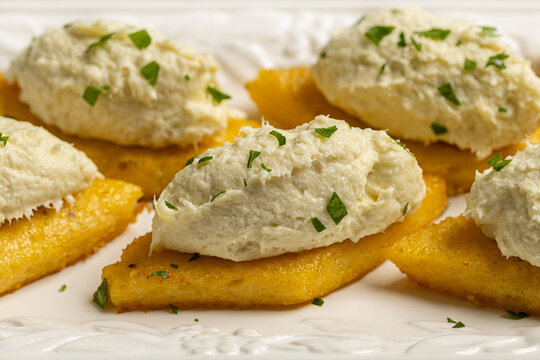 Close up of  baccala mantecato, whipped, creamed salt cod fish spread, is a Venetian appetizer made with dried cod, served on fried polenta croutons.