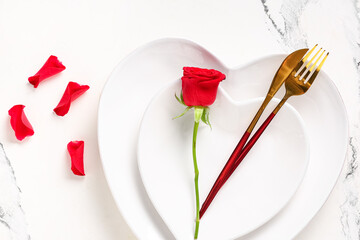 Table setting for Valentine's Day with rose flower and petals on marble background