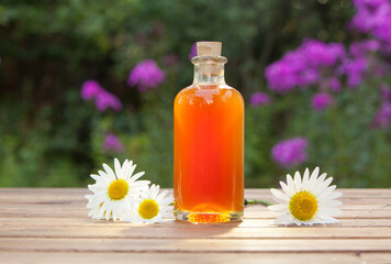 Essence of flowers on table in beautiful glass bottle