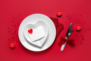 Table setting for Valentine's Day with blank paper card, burning candles and confetti on red...