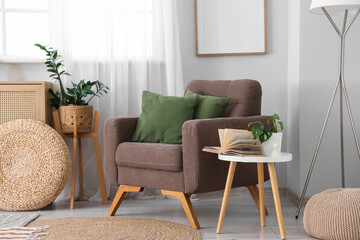 Interior of light living room with window, commode and armchair