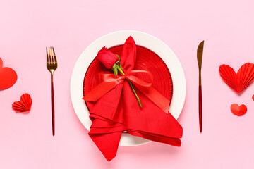 Beautiful table setting for Valentine's Day with rose flower and decorative hearts on pink...