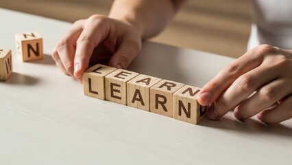 Hands arranging wooden blocks to spell the word LEARN on a table