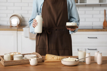 Young woman with different dairy products at table in kitchen