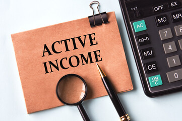 ACTIVE INCOME - words on a brown sheet on the background of a calculator