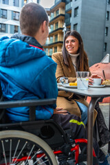 Obraz premium Woman talking with disabled boy in wheelchair at cafe