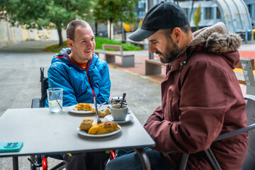 Young man with disability enjoying coffee with friend
