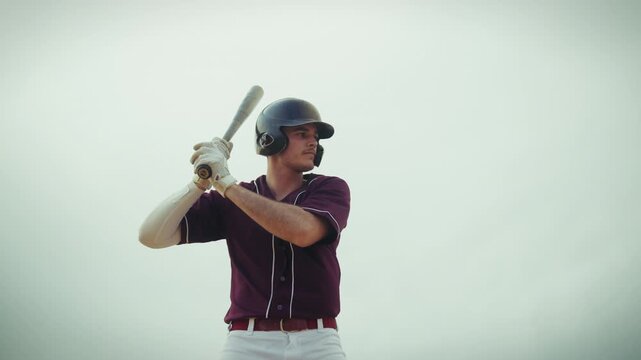 A focused baseball batter in uniform and helmet stands ready, then executes powerful practice swings with his bat, aiming for a strong hit in this dynamic sports action shot.