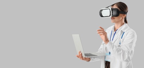 Female doctor in VR glasses and with laptop on light background with space for text