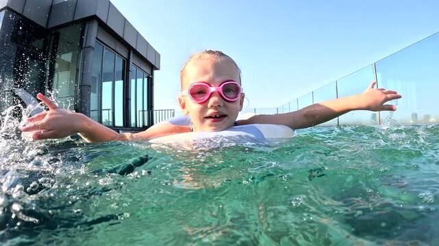Young girl enjoys swimming in rooftop pool on sunny day in city